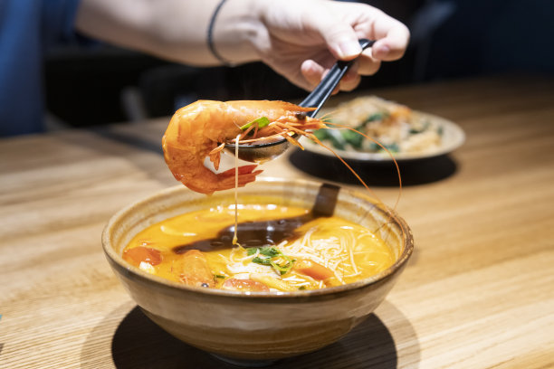 一只手用勺子拿着冬阴功的虾图片下载