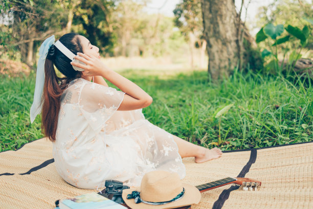 一个戴着耳机的女孩在森林里听着音乐跳舞。音乐爱好和野餐概念。图片下载