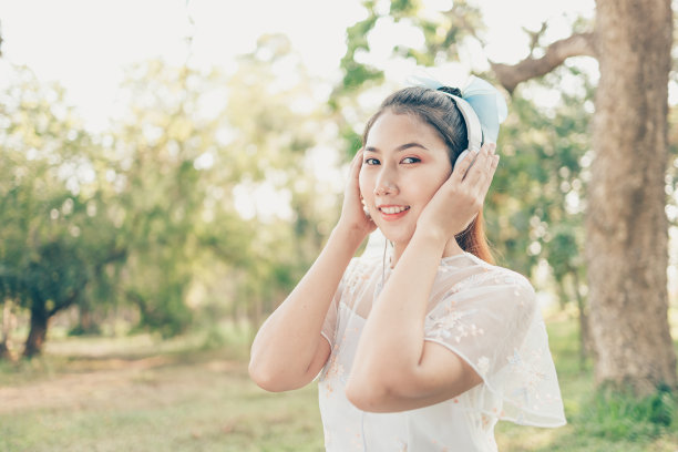 一个戴着耳机的女孩在森林里听音乐跳舞。音乐爱好和野餐概念。图片下载