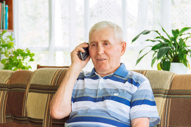 一个老年人的特写与灰色头发的男人坐在沙发上和讲手机图片下载
