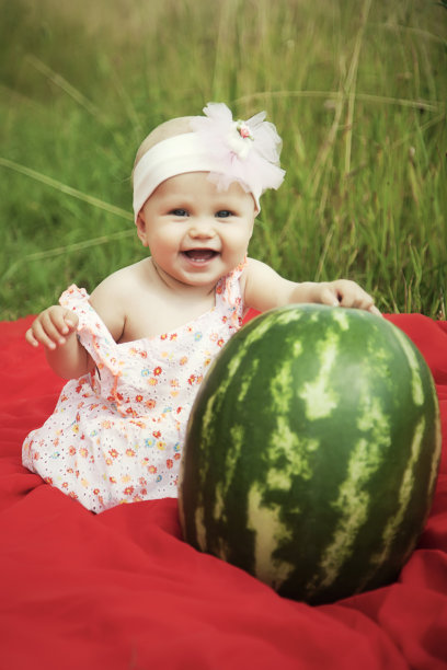 可爱快乐的金发碧眼女孩8个月在草和西瓜图片下载