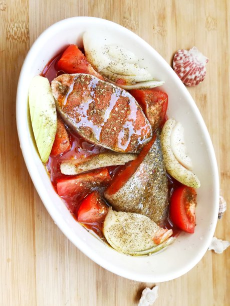 用白色盘子盛着蕃茄和洋葱的鲑鱼。图片下载