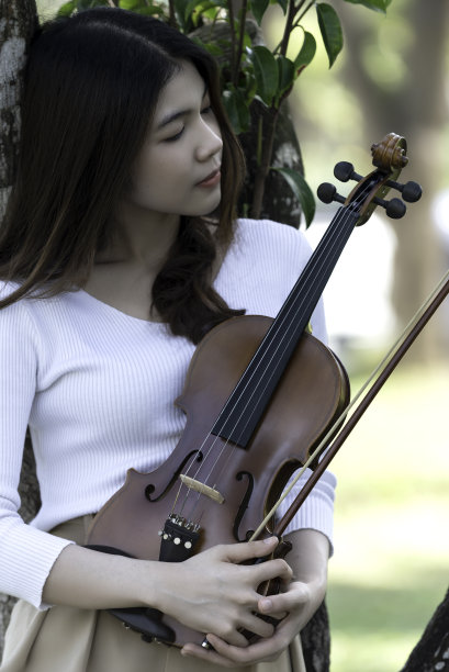 美丽的女子捧着小提琴，在自然风景的背景下，在情感上感受着幸福。图片下载