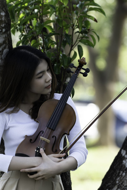 美丽的女子捧着小提琴，在自然风景的背景下，在情感上感受着幸福。图片下载