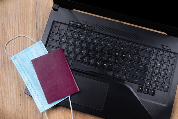木桌背景，笔记本电脑，旁边有医用防护口罩和护照。疫情期间旅行安全的新常态。飞行机票在线。旅游,度假图片下载