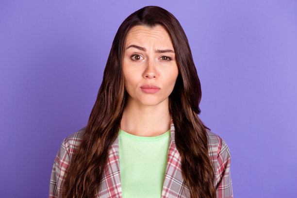 照片的困惑可疑的年轻女子挑起眉毛穿格子衬衫孤立在紫罗兰色的背景图片下载