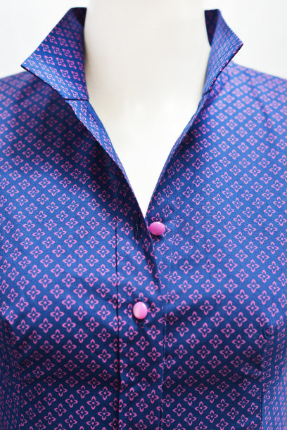 连衣裙胸前有衣领和粉红色的纽扣扣。蓝色背景上的淡紫色图案。棉布。图片下载