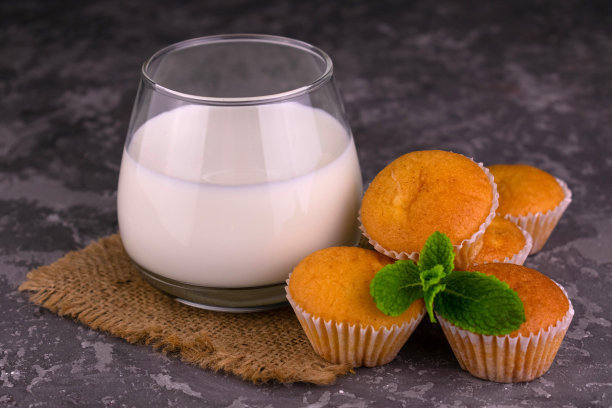 灰色背景上的一杯牛奶和小松饼。特写镜头。图片下载