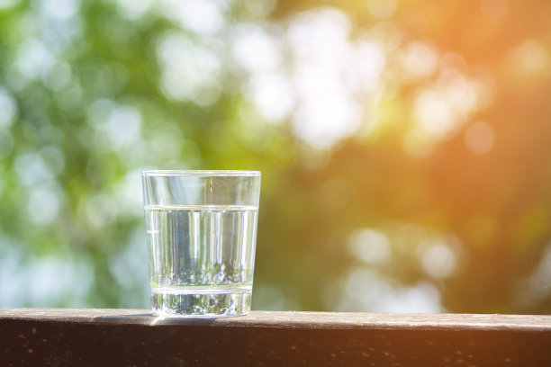 水杯放在阳光下的木板上。水合在炎热的夏天概念。健康的生活方式的象征。健康水喝与拷贝空间晴天图片下载