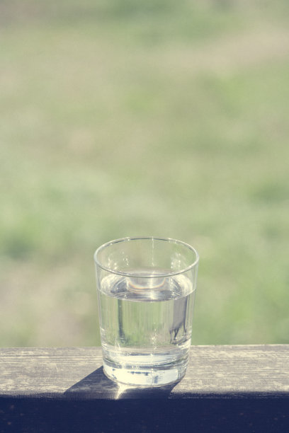 水杯放在阳光下的木板上。水合在炎热的夏天概念。健康的生活方式的象征。健康饮水调色垂直图片下载