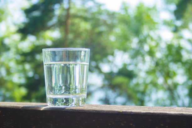 水杯放在阳光下的木板上。水合在炎热的夏天概念。健康的生活方式的象征。健康的水饮料与复制空间图片下载