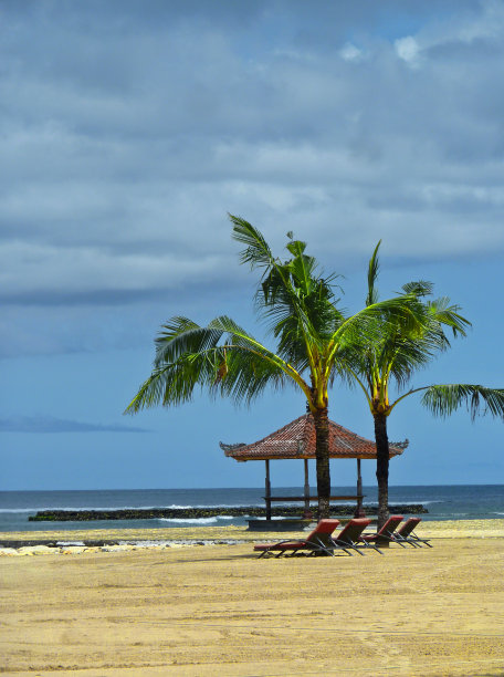 沙滩上两棵孤独的棕榈树，无人居住的沙滩上空荡荡的凉亭，无人晒太阳的懒人，宁静的风景图片下载
