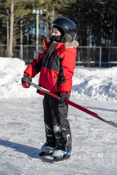 可爱的男孩在学滑冰和打冰球在后院冬天图片下载