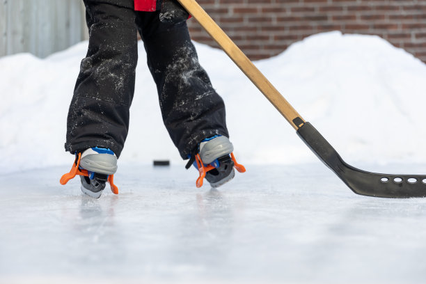 可爱的男孩在学滑冰和打冰球在后院冬天图片下载