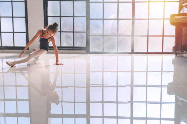 芭蕾舞女演员可爱的小女孩穿着黑色的芭蕾舞享受在工作室跳舞。可爱的小女孩在室内摆姿势跳芭蕾舞，反射在瓷砖地板上。图片下载