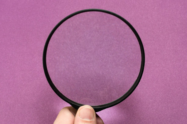 在紫罗兰色背景上的放大镜。特写镜头图片下载