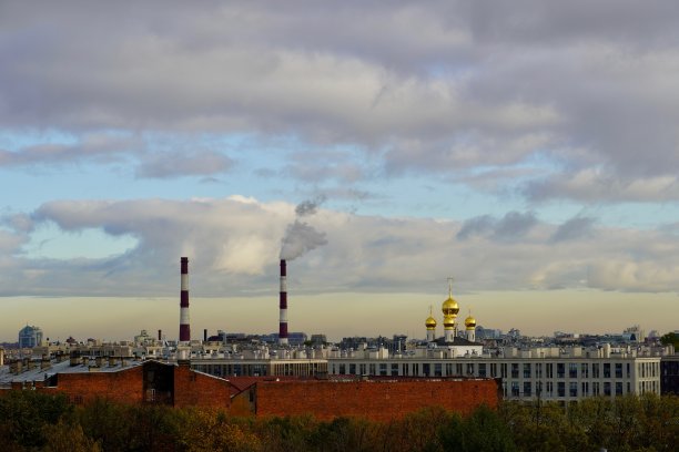 一个工业城市景观和一个有烟筒的钢铁厂和一个多云的天空作为背景。城市景观的对比——植物的管道和教堂的圆顶映衬着美丽的天空。这张照片拍摄于俄罗斯圣彼得堡图片下载