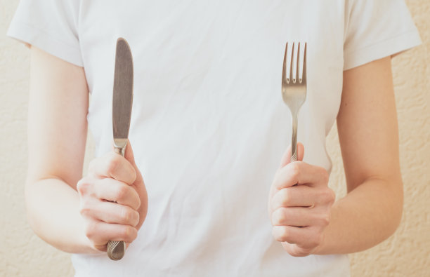 一个女人的手拿着叉子和刀孤立在一个白色的背景图片下载