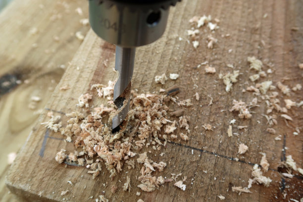 用布莱德角钢钻头钻成木板或枕木，四周镶有木屑图片下载