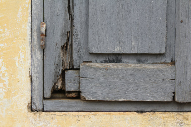 非洲黄色墙壁上的木质百叶窗，饱经风霜，状况不佳图片下载