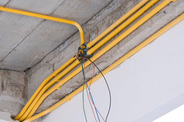 一组pvc多线管黄色电灯系统管安装在混凝土毛坯墙上，用于住宅现场建筑。维修管路的固定。图片下载