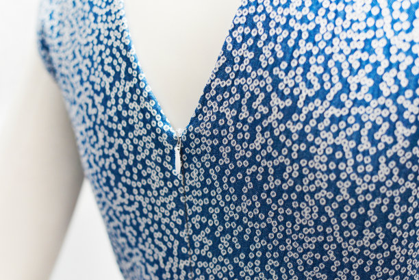 这件衣服的领口在背后有拉链。带有白点的蓝色牛仔布。白色背景。图片下载