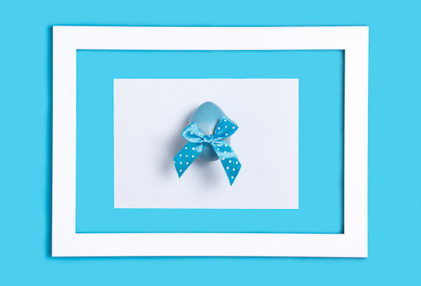 带蓝色圆点蝴蝶结的复活节彩蛋。蓝色背景的框架图片下载