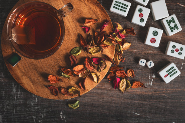 茶时间俯视图照片与杯子，茶袋和麻将牌为背景。图片下载
