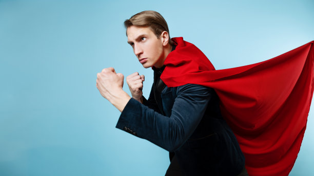 超级英雄保护。一个穿着西装，披着红斗篷的年轻人，超人。图片下载