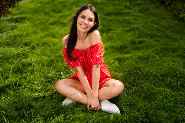 丰满的照片迷人迷人的黑发女人坐在草地草坪穿红色的裙子在公园外面图片下载