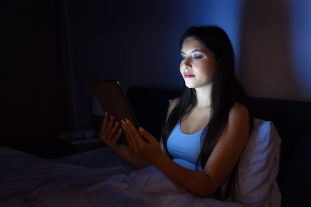 黑发女子躺在床上，在平板电脑上看书图片下载
