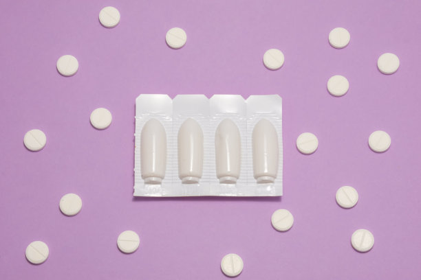 药物栓剂是用塑料包装的，背景是紫丁香色或紫色，周围是药丸。妇科、肛肠科、泌尿科的概念照片图片下载