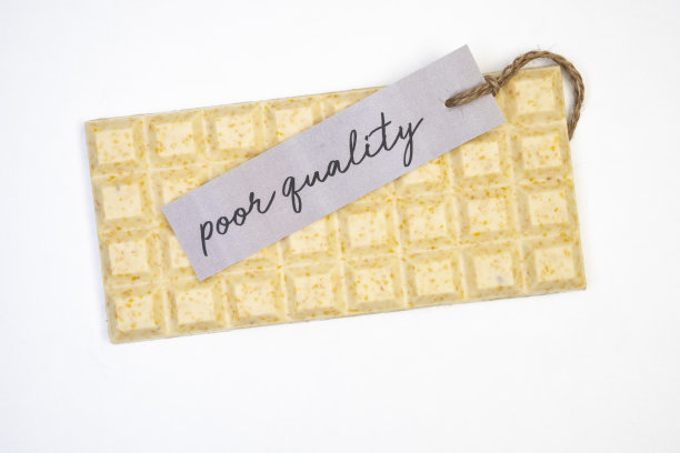 甜和美味的整个巧克力棒躺在白色的背景与一个小标签上写的质量差图片下载