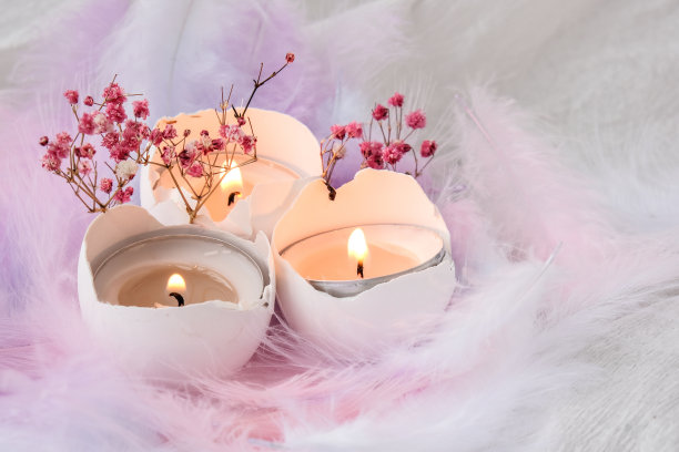 由白色蛋壳组成，里面有蜡烛。烛光。用鸟羽毛装饰的明亮的复活节装饰。柔和的颜色。复活节贺卡图片下载