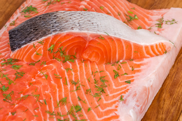 把生鲑鱼切成薄片放在切板上的鲑鱼片上图片下载