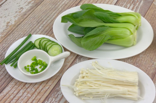 桌上的各种食材：小白菜、葱花、金针菇和黄瓜片，素食概念素材图片
