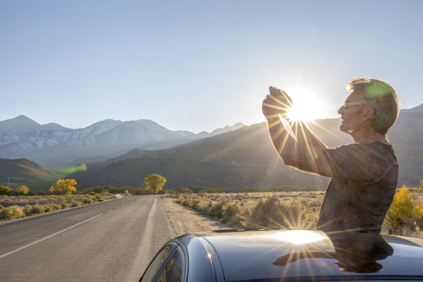 日落时分，一名男子在高速公路上用智能手机拍照图片下载