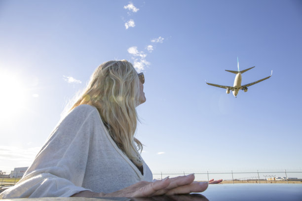 女人抬头看着飞机到达机场图片下载