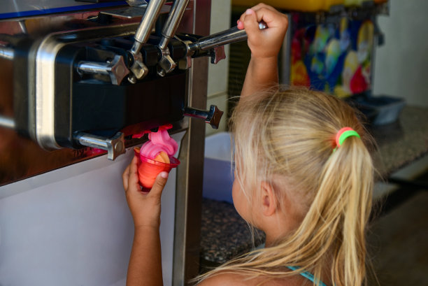 女童在海滩的自动售货机上取冰淇淋图片下载