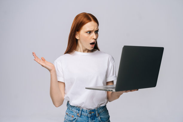 惊讶的年轻女商人或学生张大了嘴，保持着打开的笔记本电脑图片下载