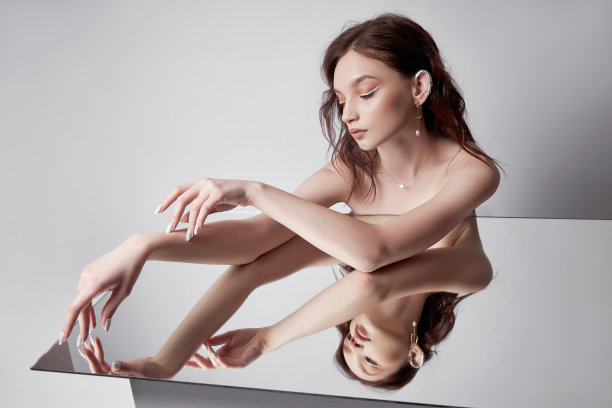 美女肖像美女躺在镜子上。自然妆容，珠宝戒指戴在手指上图片下载