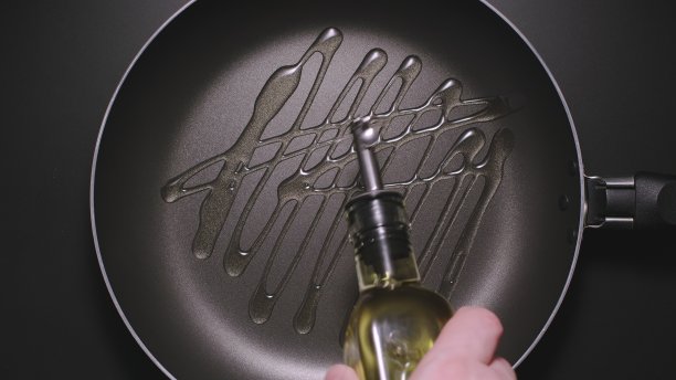 俯视图:在黑色煎锅上倒油的人图片下载