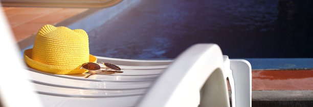 沙滩饰品，黄色帽子和太阳镜躺在泳池边的白色躺椅上。防晒、防紫外线、晒黑、旅行。度假概念，海上旅行，游泳。副本的空间。Flatlay图片下载