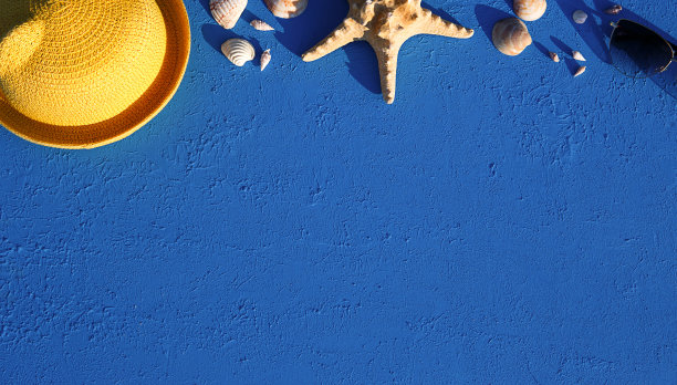 以海洋主题的沙滩饰品为框架:黄色草帽、太阳镜、海星和贝壳在蓝色背景上。度假理念、海上旅行、防紫外线、游泳。副本的空间。Flatlay图片下载
