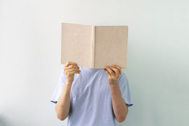 16、青年捧着一本书，读书而获得知识，站在墙边，与世隔绝图片下载