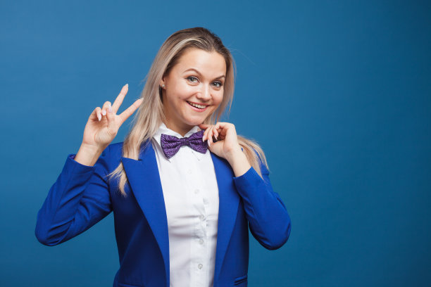 蓝色背景上穿着蓝色衣服的快乐微笑的年轻女子。友好的商业肖像图片下载