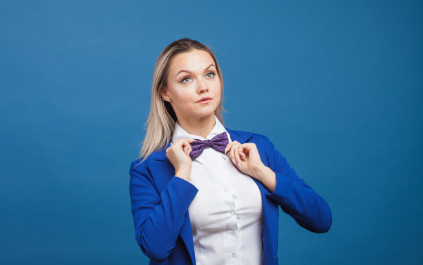 蓝色背景上穿着蓝色衣服的快乐微笑的年轻女子。友好的商业肖像图片下载