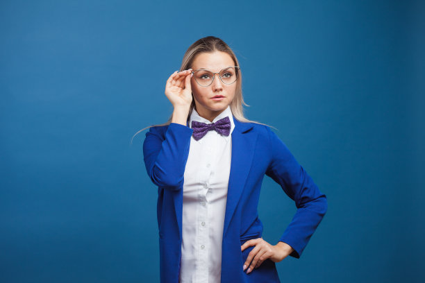 穿着时尚的蓝色夹克，打着领结的女商人正调整着她的眼镜。图片下载