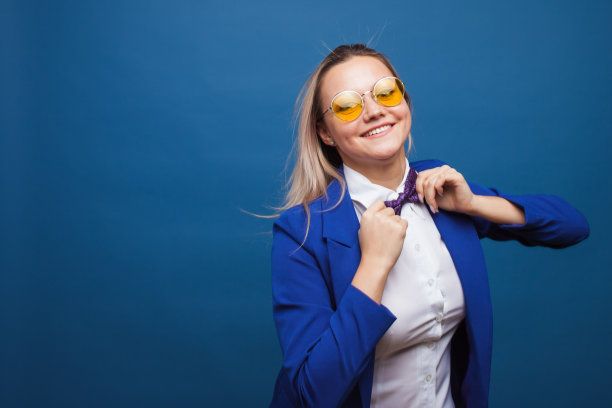蓝色背景上穿着蓝色衣服的快乐微笑的年轻女子。友好的商业肖像图片下载