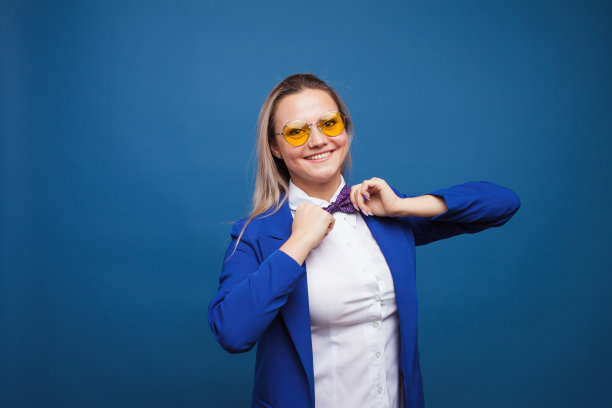 蓝色背景上穿着蓝色衣服的快乐微笑的年轻女子。友好的商业肖像图片下载